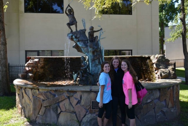 Three young women posing in front of the Hendrix fountain at CreekFest