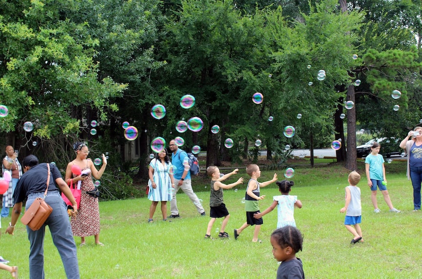 Families and children playing with bubbles outdoors at a Cypress Creek FACE event